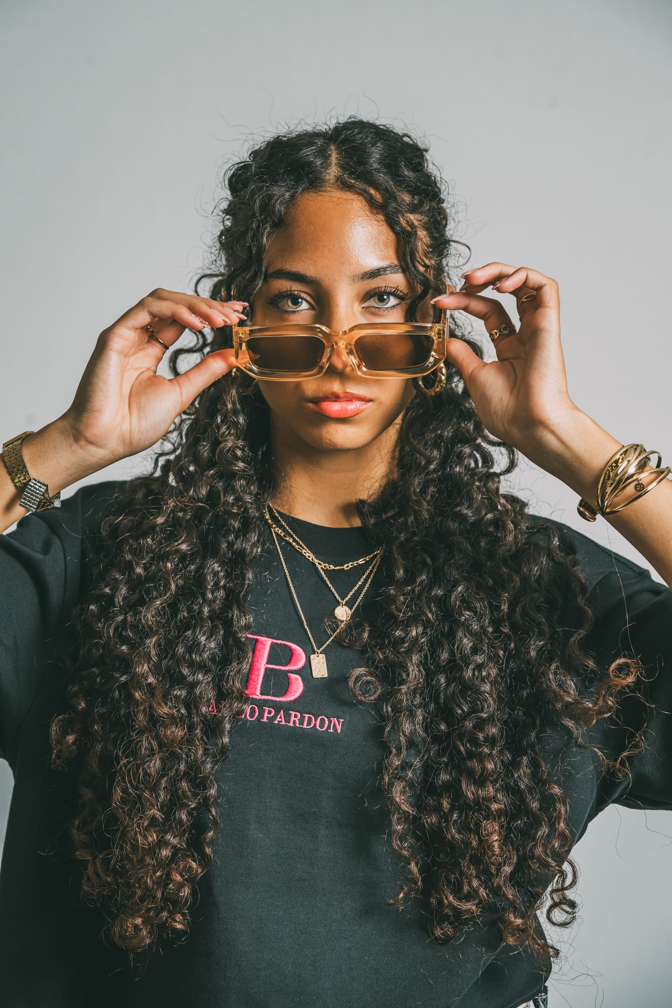 Woman in a black BLANCO PARDON T-shirt holding Dune sunglasses