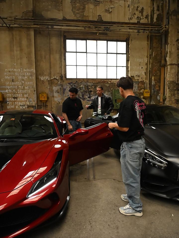 BLANCO PARDON crew next to a red Ferrari in a garage