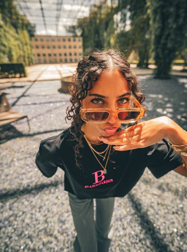 Woman in a black BLANCO PARDON T-shirt with Dune sunglasses
